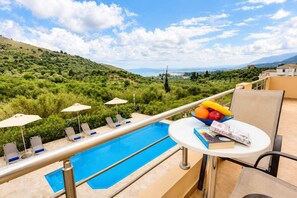 A poolside area with lounge chairs, umbrellas, and a table with fruits and a book. - Oceana Suites Villas - Private Pool Hideaway (Apokoronas)