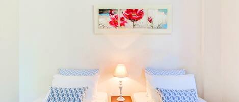 Una camera d'albergo con due letti, un comodino con una lampada e un quadro appeso al muro.