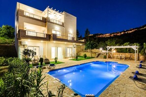 A modern two-story building with a swimming pool, outdoor seating, and a stone pathway. - Oceana Suites Villas - Cozy Sea View Suite (Apokoronas)
