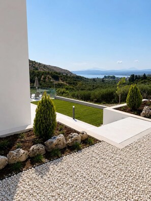 Eine moderne Terrassengestaltung mit Blick auf eine hügelige Landschaft und ein Gewässer.