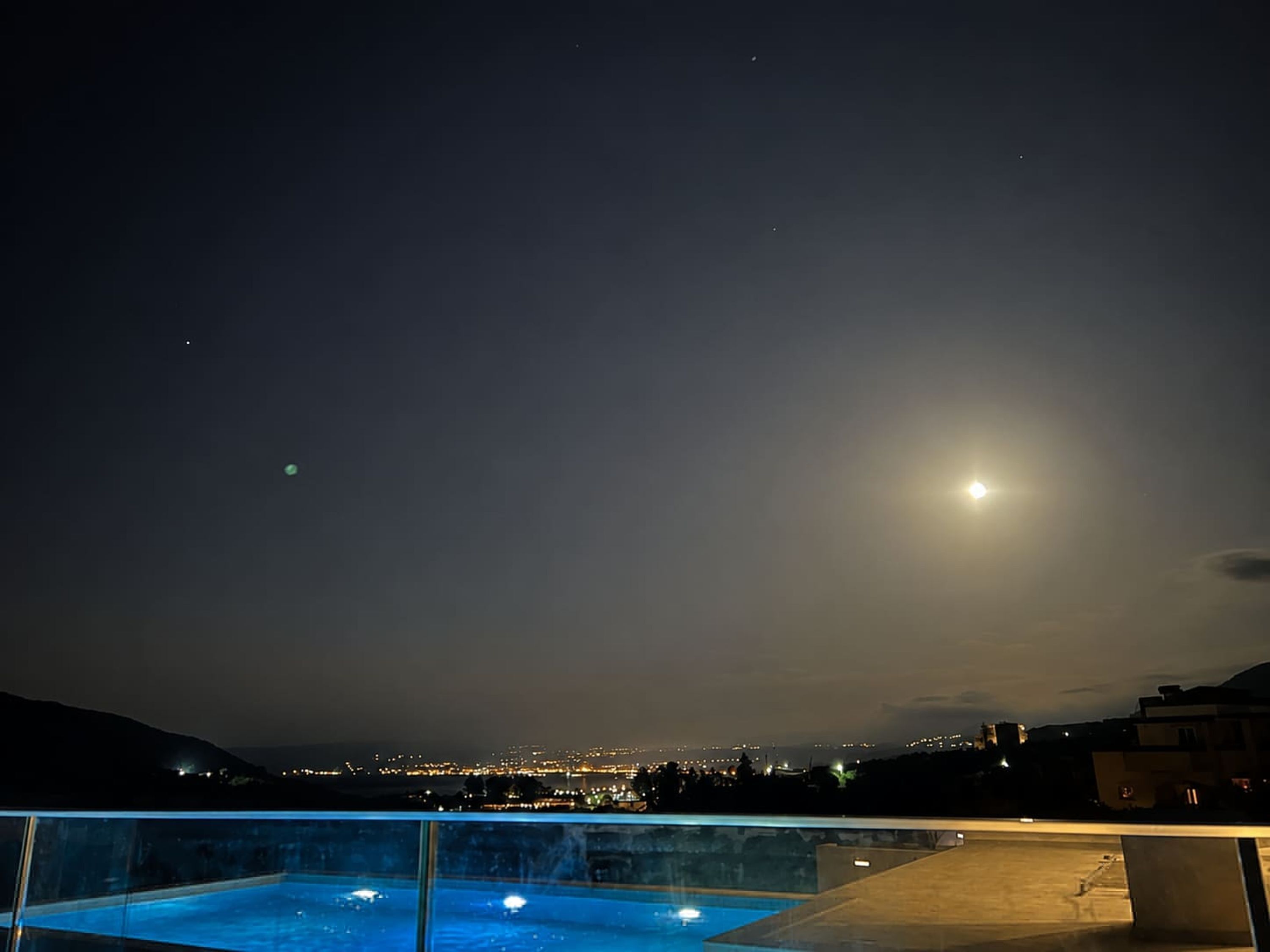 A rooftop pool with a cityscape view at night.