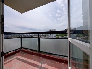 Ein Balkon mit Blick auf eine Stadtansicht, inklusive Gebäude und Grünflächen.