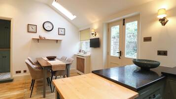A modern kitchen with a wooden table, a bowl on the counter, and a window with a view.