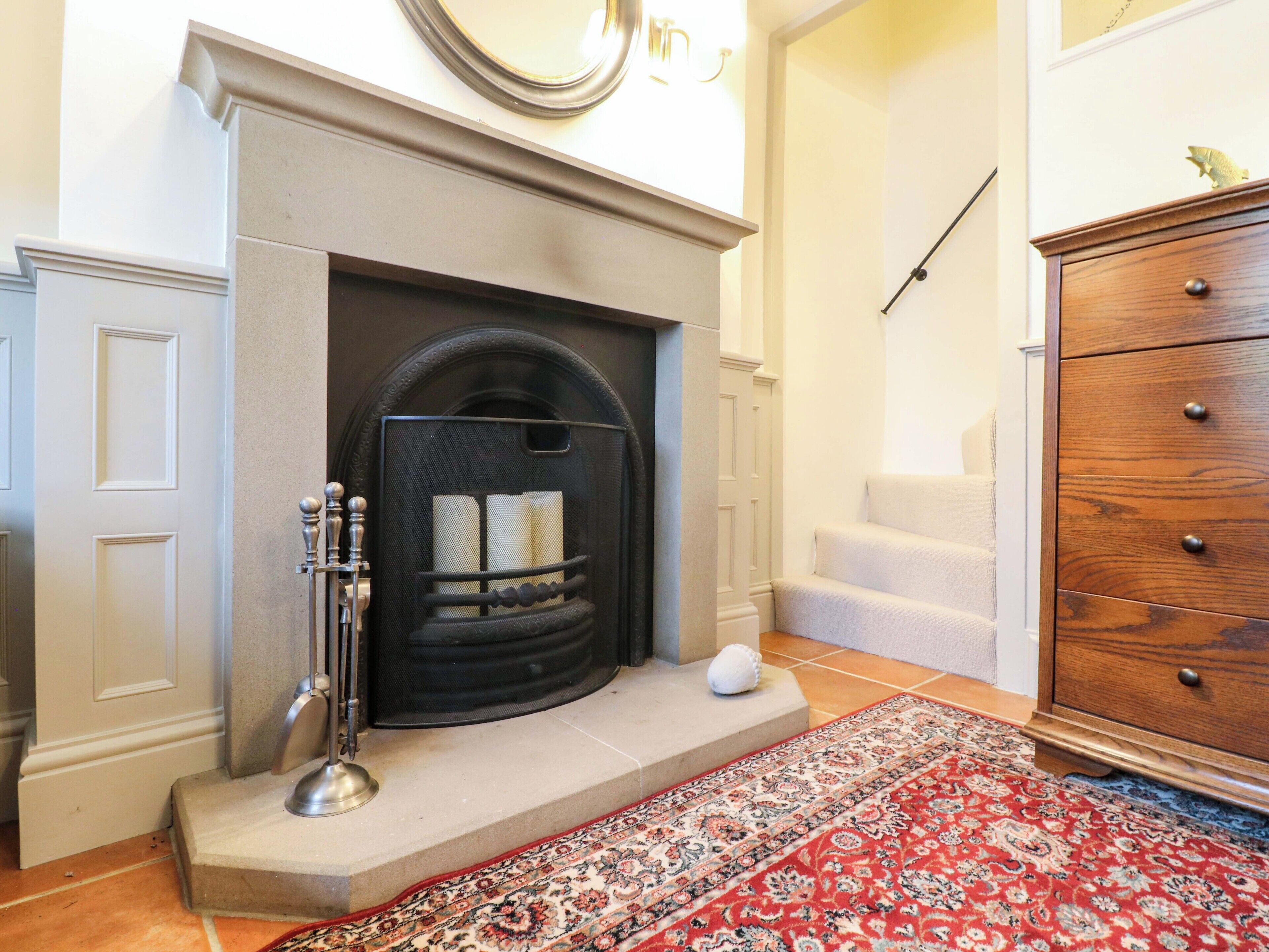 Una chimenea con protector, un mueble de madera y una alfombra estampada.