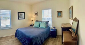 Une chambre à coucher comprenant un lit, deux tables de chevet, une commode et un miroir.