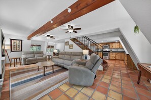 A spacious living area with a sofa, coffee table, and a staircase leading to a kitchen. - Walk to Ramsey Canyon Preserve | The Thomas House (Hereford)
