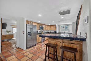 A modern kitchen with wooden cabinets, a stainless steel refrigerator, and a tiled backsplash. - Walk to Ramsey Canyon Preserve | The Thomas House (Hereford)