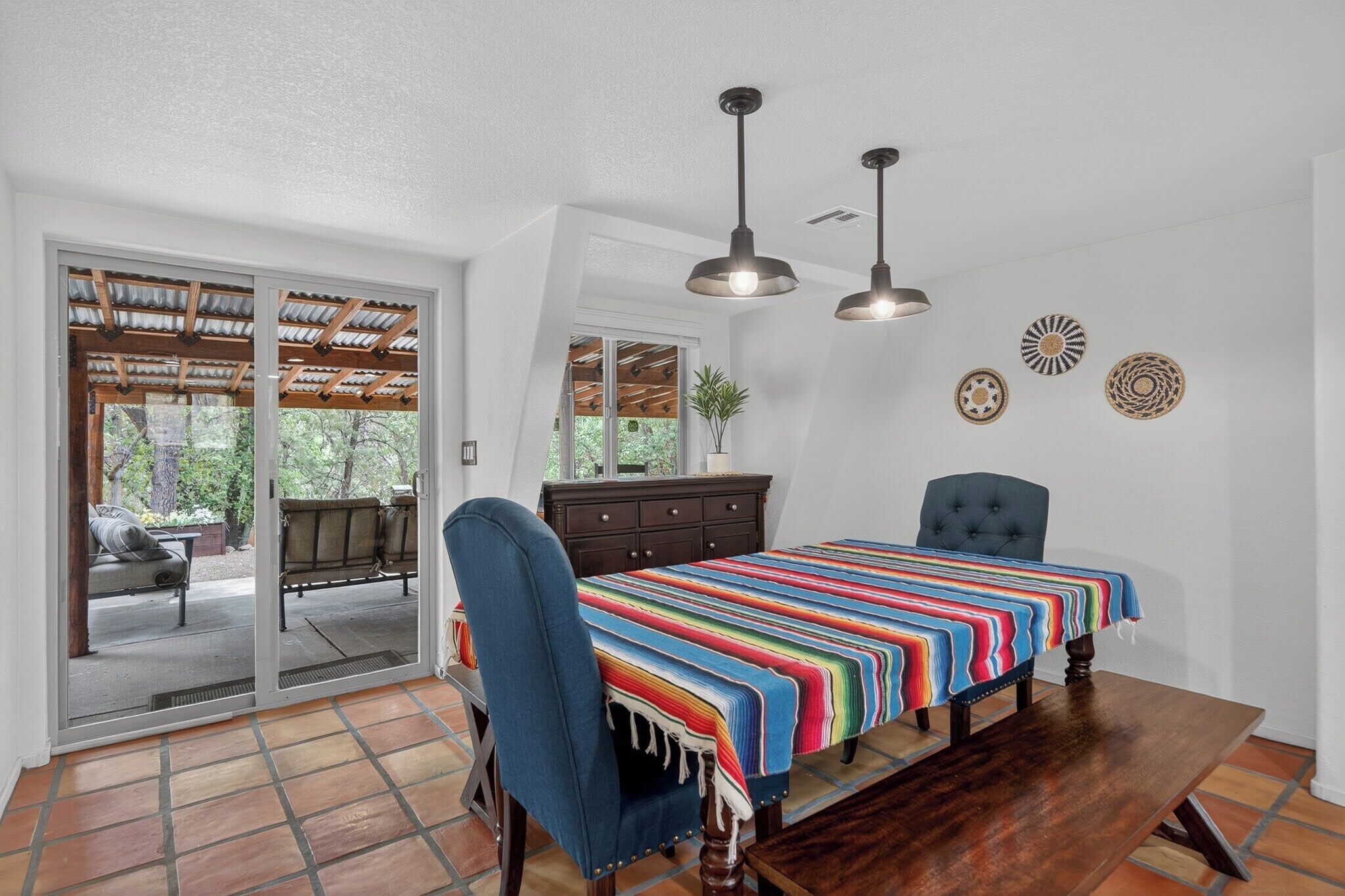 Una habitación con cama, una silla, una mesa y una puerta corrediza de vidrio que da a un patio al aire libre.