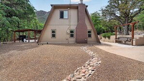 Ein Haus mit Schrägdach, Schornstein und Auffahrt mit Kies und Steinbordstein.
