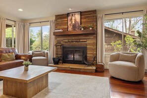 Ein Wohnzimmer mit Kamin, Ledersofa, Sessel und Couchtisch.