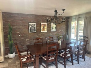 Ein Essbereich mit Backsteinwand, gerahmten Bildern, einer Chandelüster und einer Sukkulente.