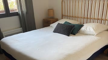 Een bed met een wit- en donkerblauwe dekbedovertrek, een houten hoofdbord en een nachtkastje met een lamp.
