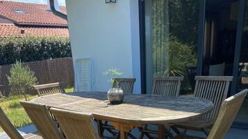 Een ronde houten tafel met stoelen, een potplant en een raam met gordijnen.
