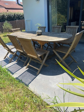 A round wooden table with chairs, a potted plant, and a window with curtains. - House located 15 minutes from the main beach in Hendaye, in a lush, peaceful setting. (Hendaye)