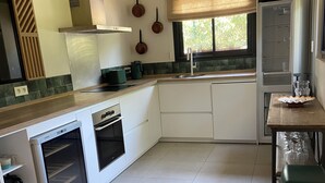 Una cocina moderna con armarios blancos, horno empotrado y ventana con vistas a zonas verdes.