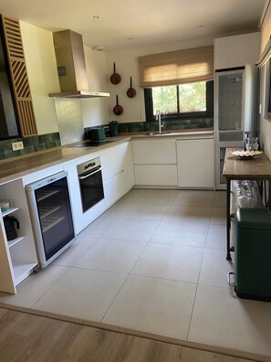 A modern kitchen with white cabinetry, a built-in oven, and a window with a view of greenery. - House located 15 minutes from the main beach in Hendaye, in a lush, peaceful setting. (Hendaye)