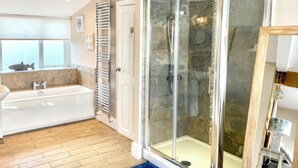 A modern bathroom with a glass-enclosed shower, a bathtub, and a window with a fish decoration. - The View (Criccieth)
