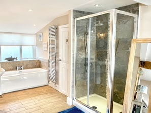 Ein modernes Badezimmer mit einer Glaskabine zur Dusche, einer Badewanne und einem Fenster mit Fischdekor.