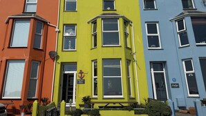 A row of colorful terraced houses with distinct architectural styles, including bay windows and dormer windows. - The View (Criccieth)