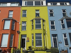 Eine Reihe bunter Reihenhäuser mit unterschiedlichen architektonischen Stilen, darunter Erker und Dachfenster.