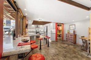 A modern kitchen with a marble countertop, red bar stools, and a view of the street outside. - Luxury Point Loma Stay - Central, Coastal & Unique (San Diego)