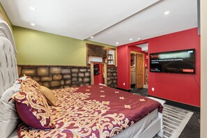 A hotel room with a large bed, a television mounted on the wall, and a stone accent wall. - Luxury Point Loma Stay - Central, Coastal & Unique (San Diego)