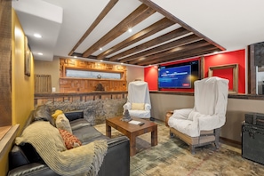 Ein gemütlicher Lounge-Bereich mit Kamin, Fernseher und bequemen Sitzmöglichkeiten.