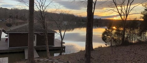 A lakeside cabin with a dock, surrounded by trees and a stone pathway.