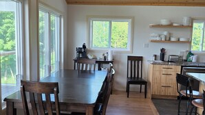 Una cocina amplia con pisos de madera, un comedor con una mesa grande y sillas, y vista a zonas verdes.
