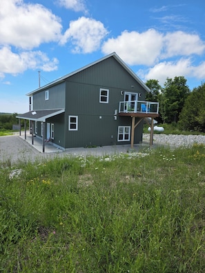 A two-story building with a balcony, a covered porch, and a gravel driveway.