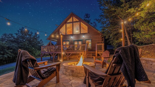 A log cabin with a stone fire pit, wooden deck, and outdoor seating. - Summit Views | Hot Tub, Sauna, Fire Pit & Game Room, Near Gatlinburg (Gatlinburg)