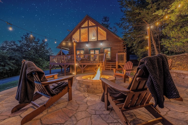 A log cabin with a stone fire pit, wooden deck, and outdoor seating. - Summit Views | Hot Tub, Sauna, Fire Pit & Game Room, Near Gatlinburg (Gatlinburg)