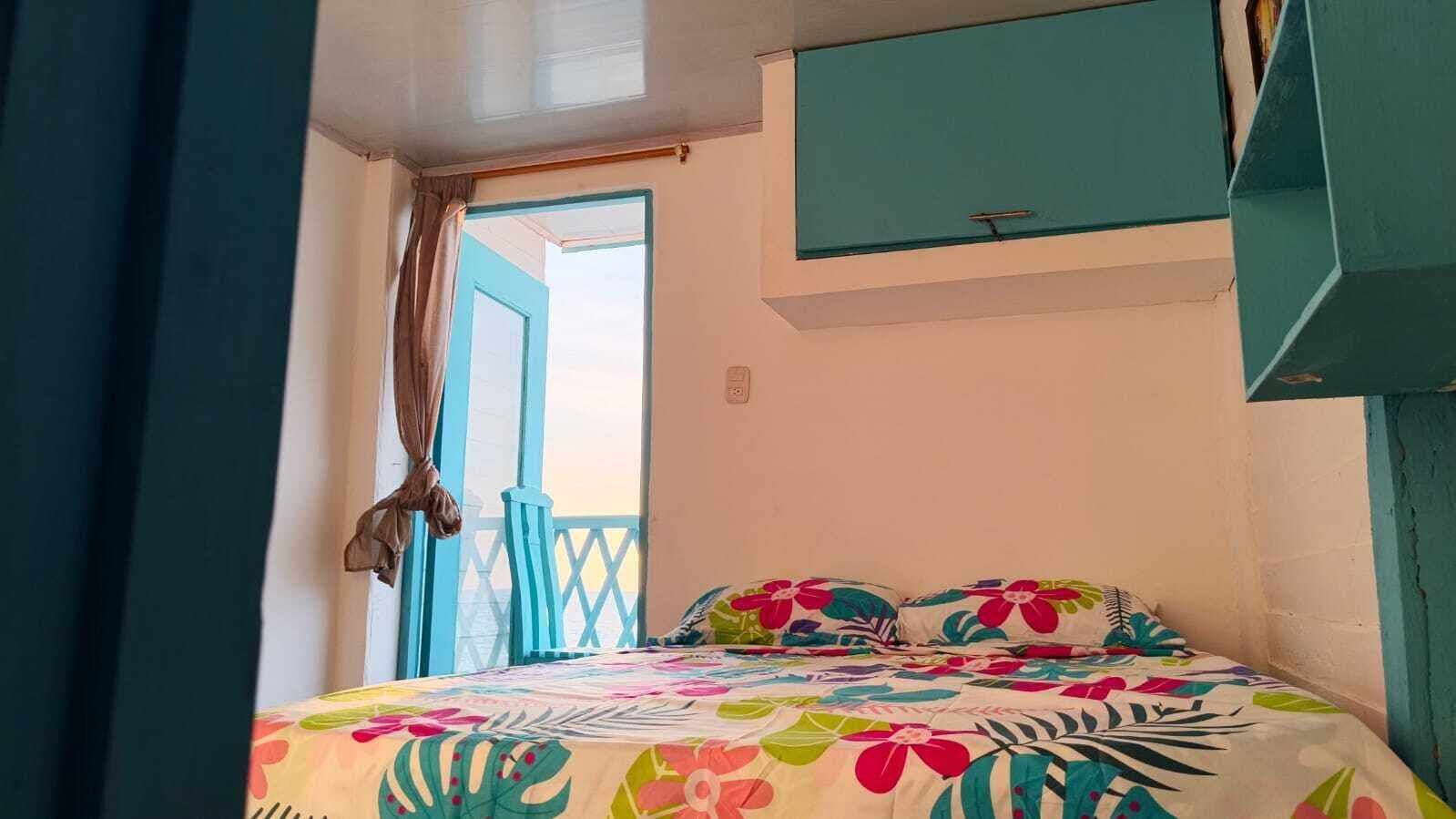 Une chambre à coucher avec un lit, une fenêtre avec des rideaux et un mur bleu.