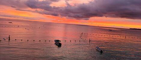 Mar tranquila al atardecer con barcos y boyas.