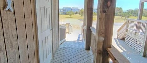 A wooden porch with a view of a parking lot and buildings in the distance.