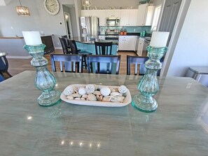 A dining area with a glass table, two candle holders, and a plate of decorative items. - 7Bed steps to ocean/Private pool & Hot tub/Pets OK (Waves)