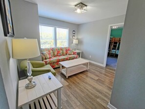 A living room with a sofa, a table with a lamp, and a wooden coffee table. - 7Bed steps to ocean/Private pool & Hot tub/Pets OK (Waves)