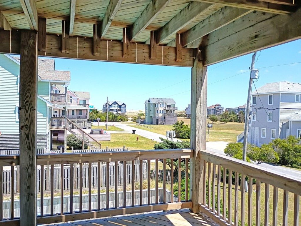 A wooden porch with a view of a residential neighborhood.
