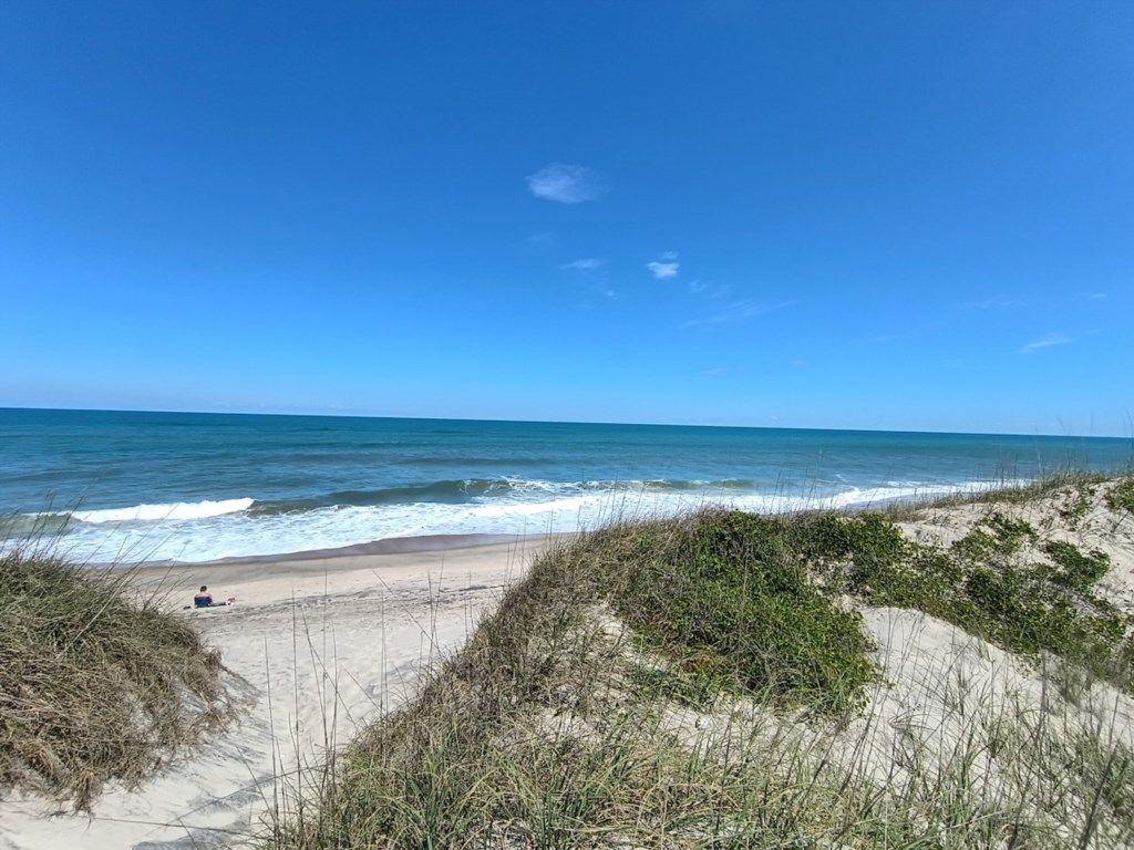A beach with sand dunes and a clear blue sky.