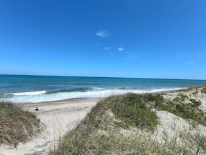 Una platja amb dunes de sorra i un cel blau clar.