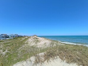 A coastal landscape with a sandy beach, dunes, and a clear blue sky. - 7Bed steps to ocean/Private pool & Hot tub/Pets OK (Waves)