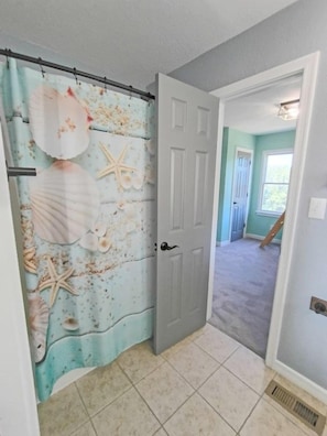 Un passadís amb una porta que dona a una habitació amb una paret de color blau clar i una finestra.