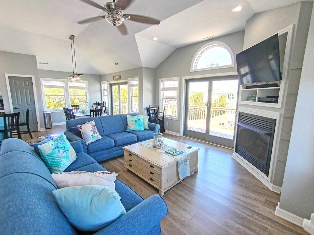 A spacious living room with a blue sofa, a coffee table, and a fireplace.