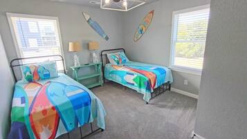 A bedroom with two beds, a ceiling fan, and surfboards on the wall.
