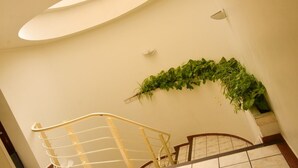 A staircase with a metal handrail, a wall-mounted light fixture, and a green plant decoration. - HOTEL MEDITERRANEO, located right in the heart of the city. Complimentary breakfast (Tulancingo)
