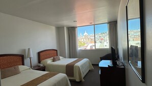 A hotel room with two beds, a desk with a computer, a TV, and a window with a city view. - HOTEL MEDITERRANEO, located right in the heart of the city. Complimentary breakfast (Tulancingo)