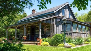 Ein rustikales Holzhaus mit Veranda, Schornstein und gepflegtem Garten.