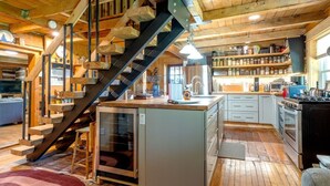 Eine rustikale Küche mit Holzbalken, einem eingebauten Herd und einer Holztreppe.