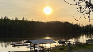 Un pavillon au bord du lac, doté d’un toit, entouré d’une eau calme et d’arbres.