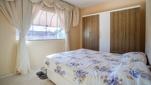 Un dormitorio con cama, cortinas, armario y ventana.